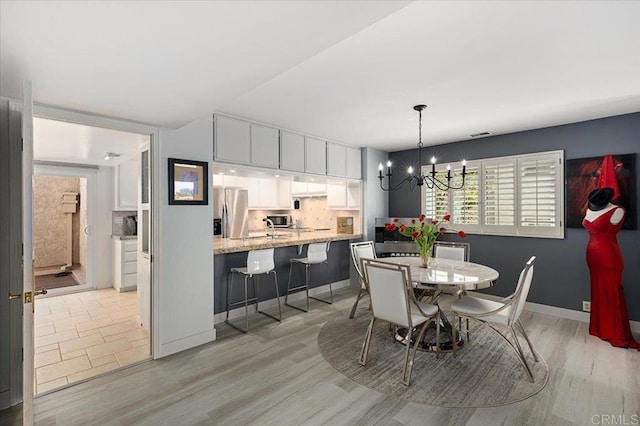 dining area featuring baseboards, light wood-style flooring, and a notable chandelier
