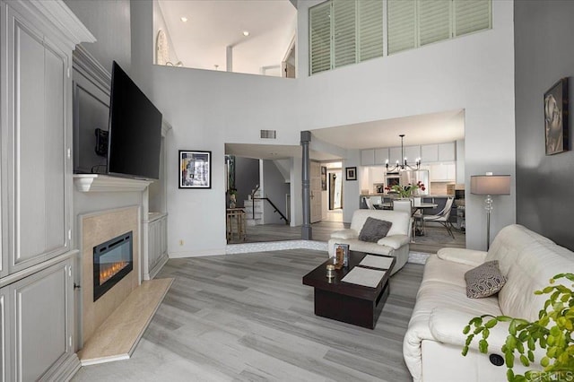 living area featuring visible vents, a high end fireplace, a towering ceiling, and a notable chandelier