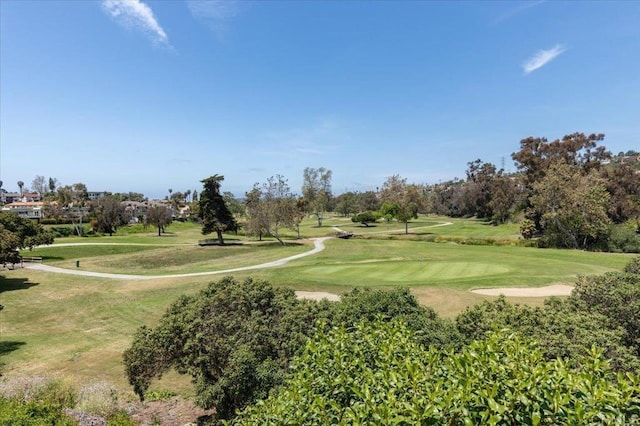 view of property's community featuring view of golf course and a yard