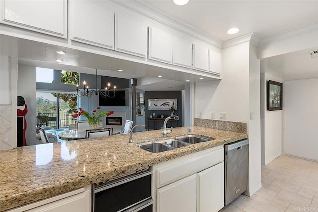 kitchen featuring stainless steel dishwasher, white cabinetry, a chandelier, and a sink
