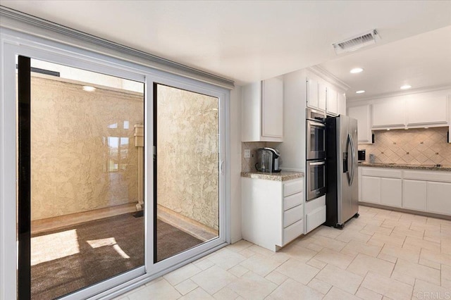 kitchen featuring visible vents, tasteful backsplash, light stone counters, stainless steel appliances, and white cabinetry