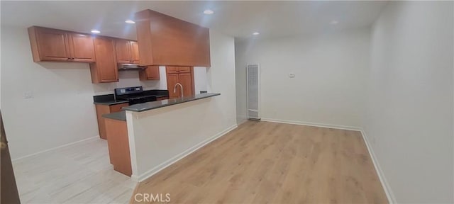 kitchen featuring brown cabinetry, a heating unit, stainless steel range with electric stovetop, baseboards, and light wood-type flooring