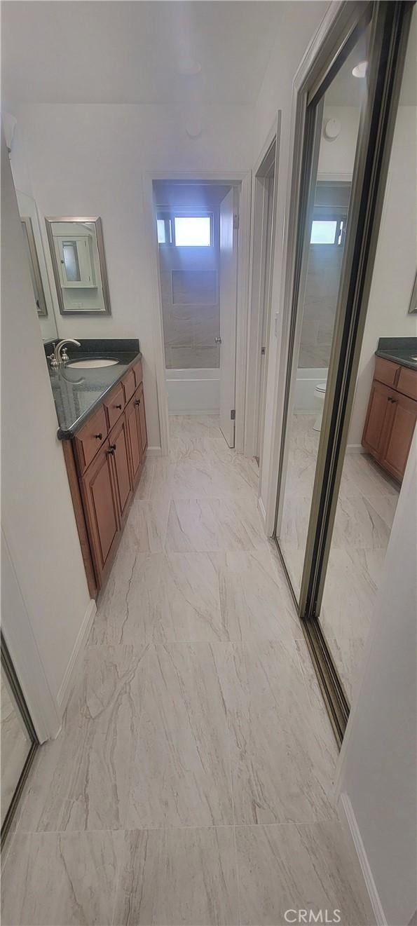 full bathroom with a stall shower, baseboards, marble finish floor, and vanity