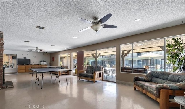 game room featuring ceiling fan, concrete flooring, a textured ceiling, and a wealth of natural light