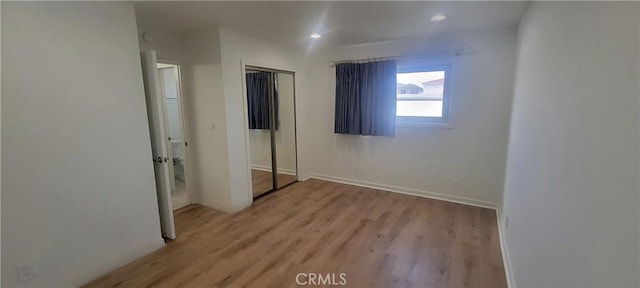 unfurnished bedroom with recessed lighting, light wood-style flooring, baseboards, and a closet