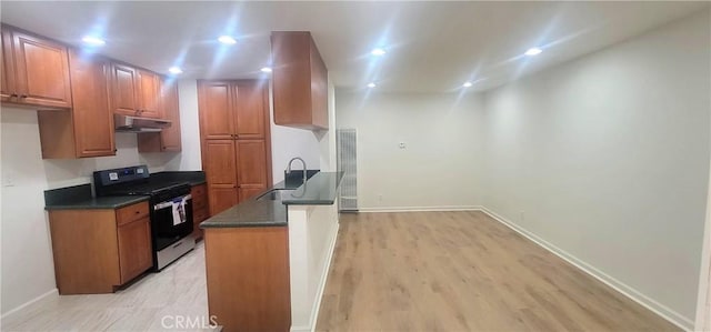 kitchen featuring dark countertops, stainless steel range with gas cooktop, under cabinet range hood, brown cabinets, and a sink