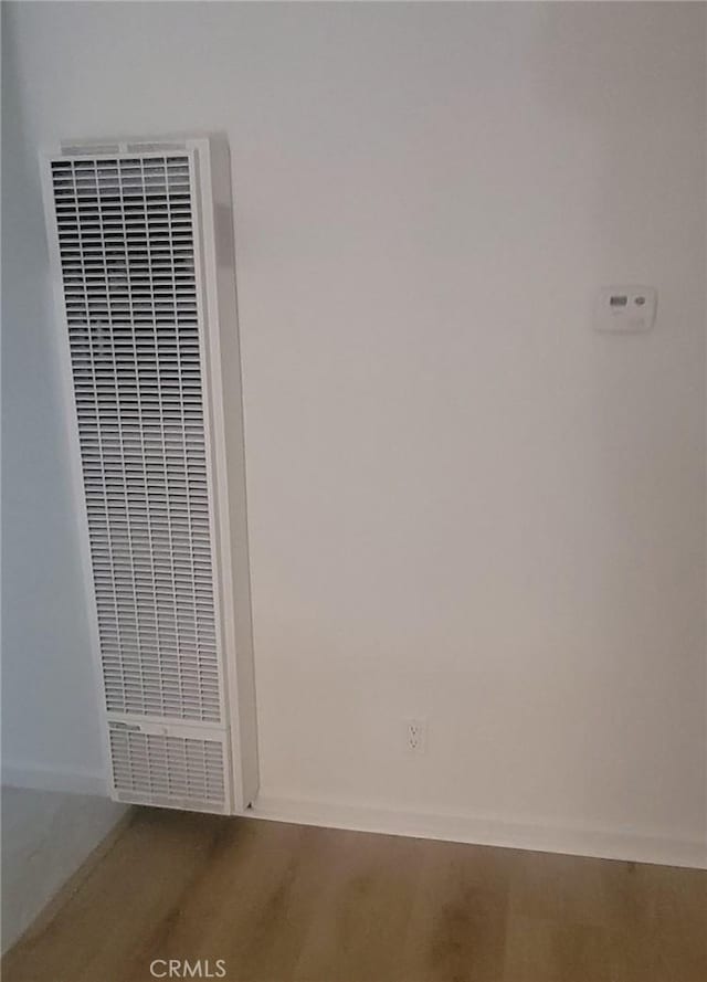 room details with a heating unit, baseboards, and wood finished floors