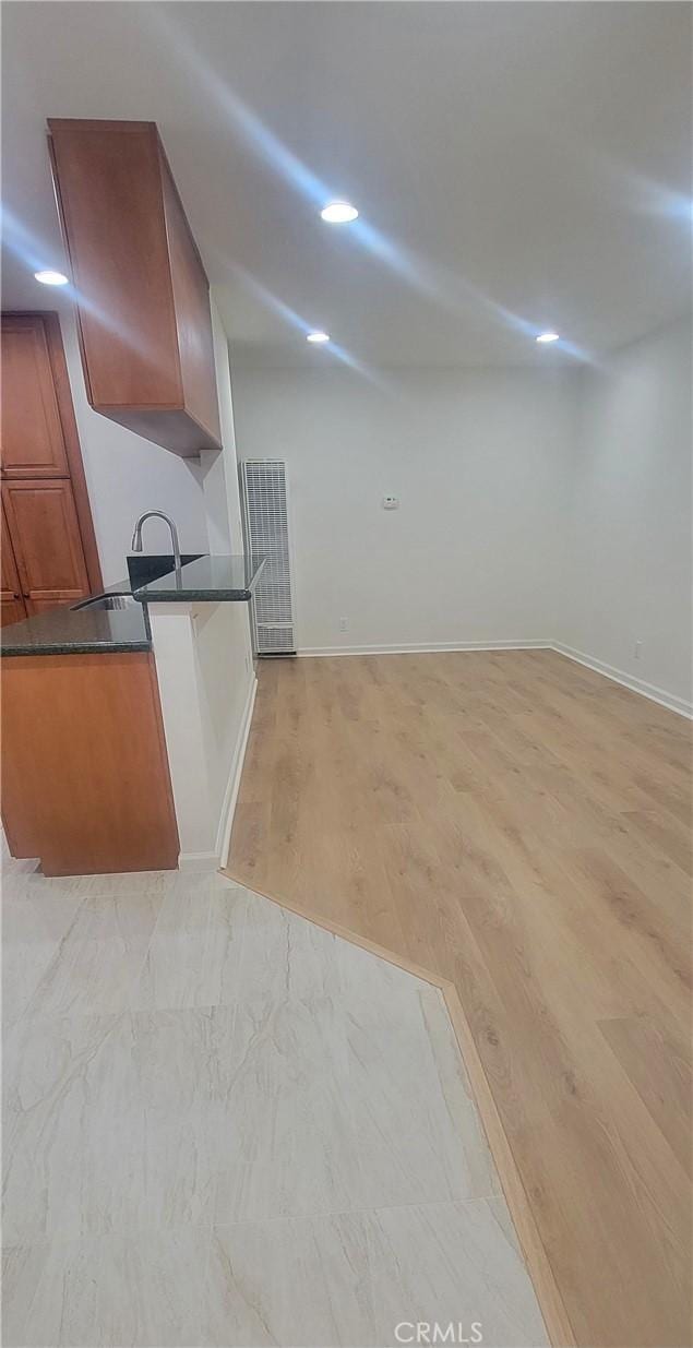 kitchen featuring a sink, dark countertops, baseboards, and brown cabinetry