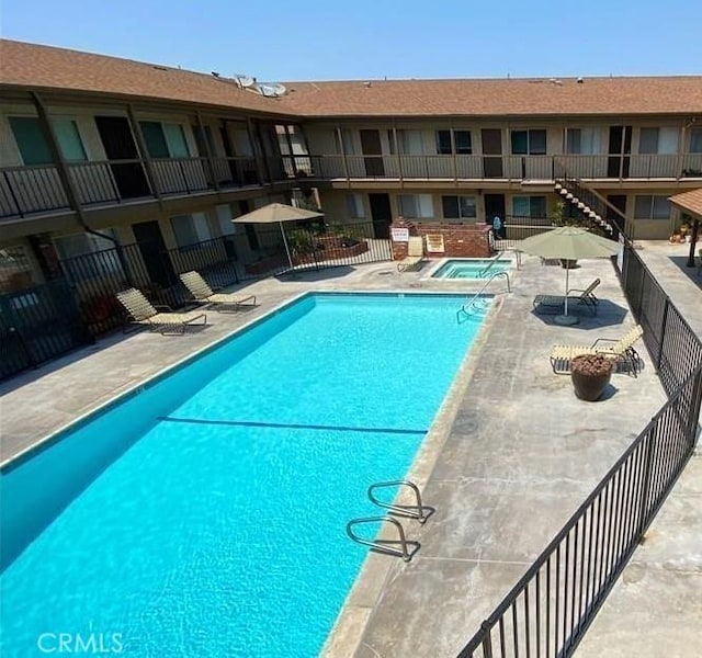 community pool featuring a patio, fence, and a community hot tub