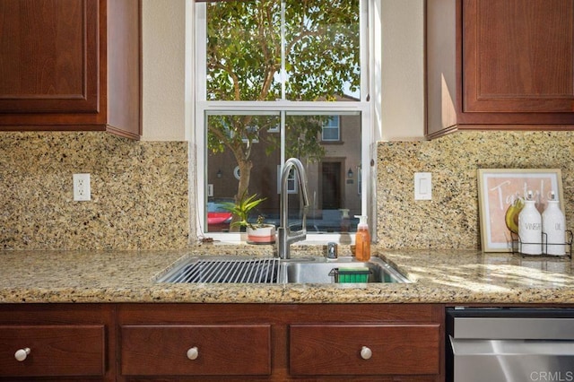 17011 Calle Trevino Unit 5, San Diego, CA 92127 - kitchen with brown cabinetry, tasteful backsplash, stainless steel dishwasher, light stone countertops, and a sink