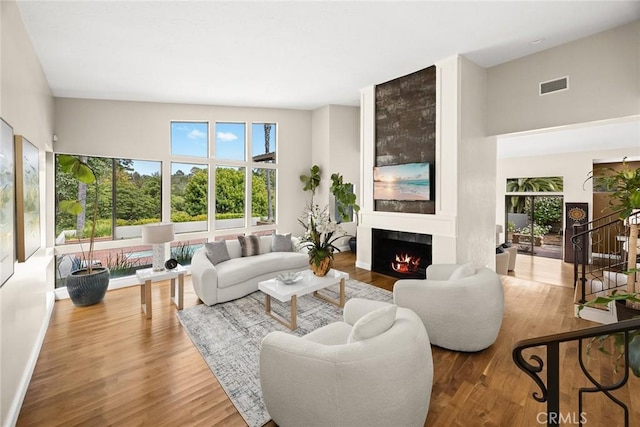 living area with baseboards, visible vents, a large fireplace, and wood finished floors