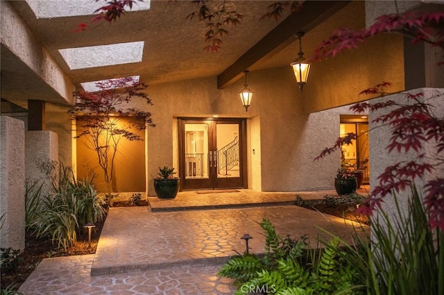 view of exterior entry featuring french doors, a patio, and stucco siding