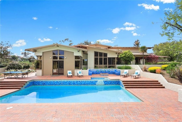 outdoor pool featuring a hot tub and a patio area