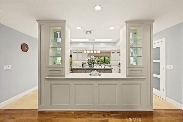 bar featuring baseboards, decorative light fixtures, wood finished floors, and visible vents