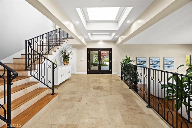 foyer entrance featuring a raised ceiling, stone finish floor, french doors, baseboards, and stairway