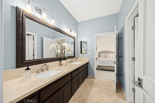 bathroom featuring double vanity, baseboards, a sink, and ensuite bathroom