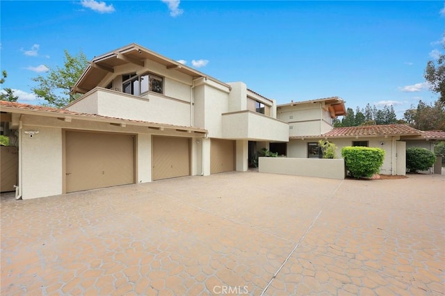 view of front of property with an attached garage, stucco siding, a balcony, and driveway
