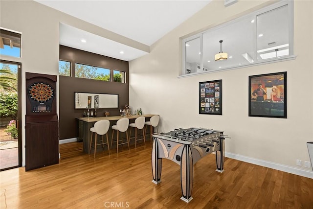 recreation room with baseboards, wood finished floors, and indoor bar