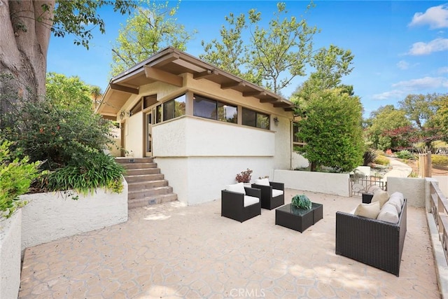 view of property exterior with an outdoor living space, a patio area, and stucco siding