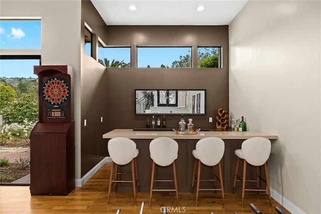 bar with baseboards, a dry bar, plenty of natural light, and wood finished floors