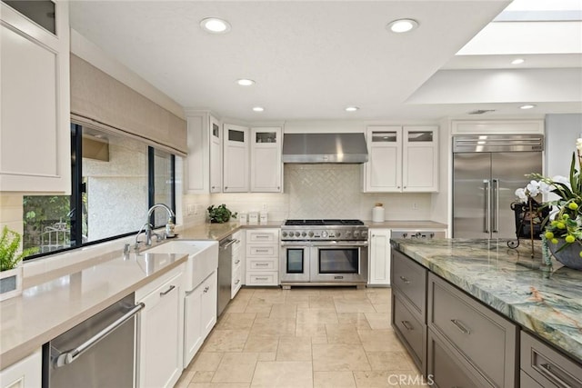 kitchen featuring exhaust hood, a sink, recessed lighting, backsplash, and premium appliances
