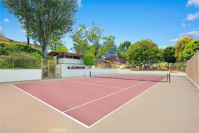 view of tennis court with community basketball court and fence