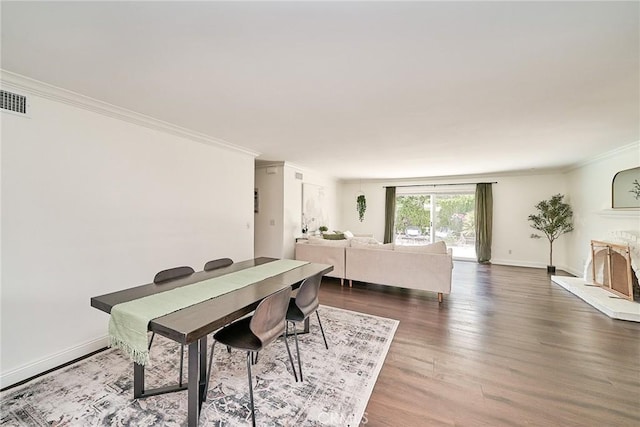 dining space featuring baseboards, ornamental molding, wood finished floors, and visible vents