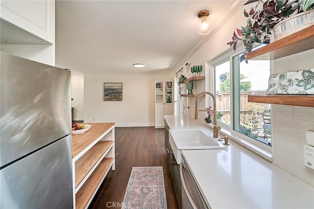 kitchen with open shelves, freestanding refrigerator, ornamental molding, light countertops, and a sink