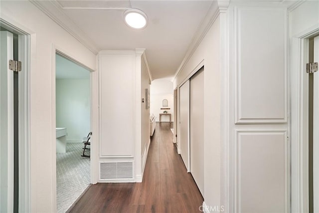 hallway with visible vents, dark wood finished floors, crown molding, and baseboards