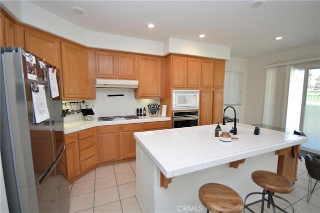 31105 Sunningdale Dr, Temecula, CA 92591 - kitchen with stainless steel appliances, under cabinet range hood, light tile patterned floors, light countertops, and recessed lighting