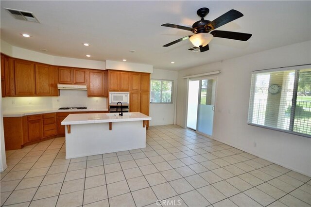 31105 Sunningdale Dr, Temecula, CA 92591 - kitchen featuring white appliances, light countertops, under cabinet range hood, brown cabinets, and recessed lighting