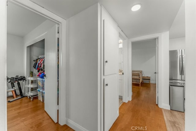 hall featuring baseboards and light wood-type flooring