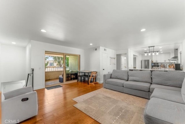 living area with baseboards, recessed lighting, light wood-style flooring, and a notable chandelier