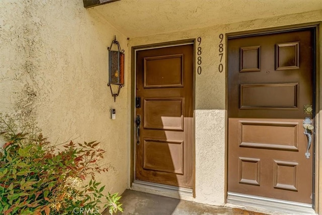 view of exterior entry with covered porch and stucco siding