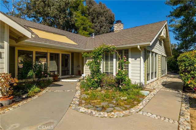 exterior space featuring a chimney and a shingled roof