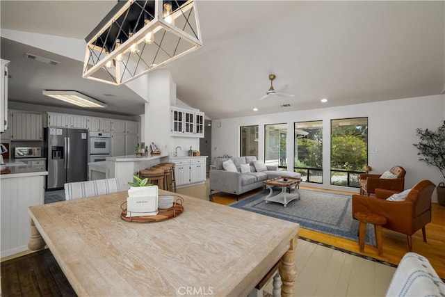 dining space featuring dark wood finished floors, visible vents, lofted ceiling, and a ceiling fan