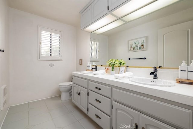 full bath featuring toilet, double vanity, and a sink