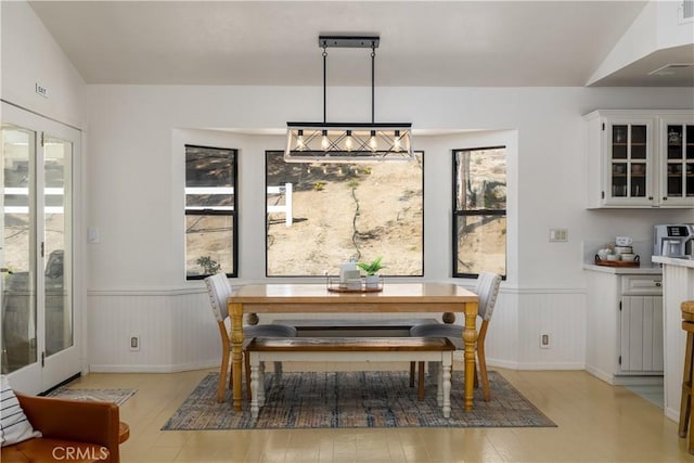 dining space with wainscoting, light wood-type flooring, and visible vents