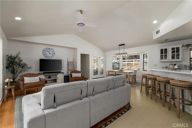 living area featuring vaulted ceiling, ceiling fan, light wood-style flooring, and visible vents