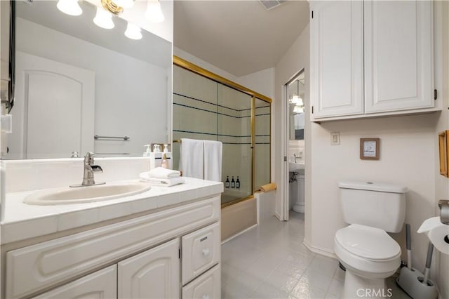 bathroom with toilet, baseboards, tile patterned floors, vanity, and combined bath / shower with glass door