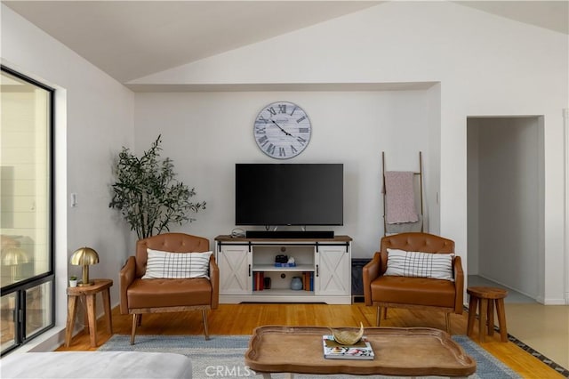 living area with wood finished floors and vaulted ceiling