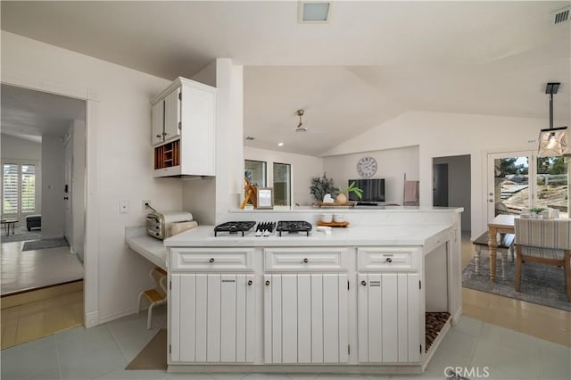 kitchen with a peninsula, visible vents, vaulted ceiling, white cabinetry, and a ceiling fan