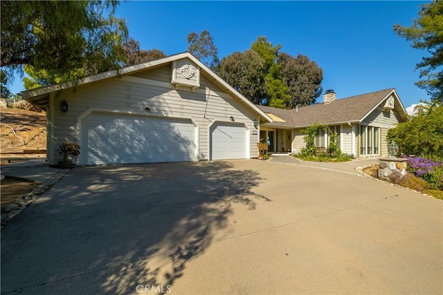 ranch-style home featuring a chimney, driveway, and an attached garage