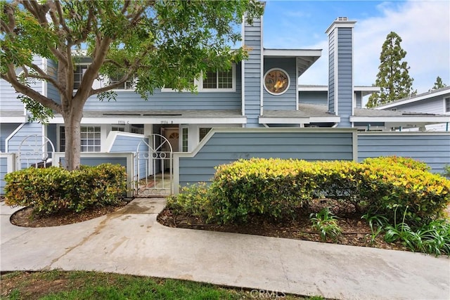 multi unit property with a gate, fence, and a chimney