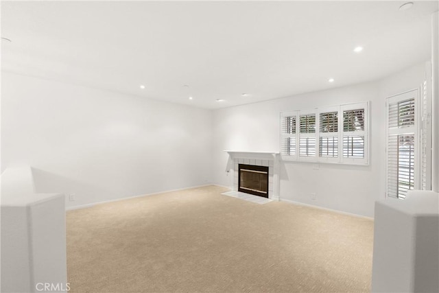 unfurnished living room featuring baseboards, carpet flooring, recessed lighting, and a tile fireplace