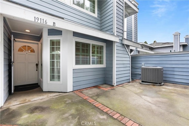 property entrance featuring central air condition unit, fence, and a patio