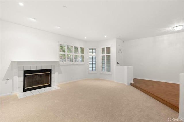 unfurnished living room with recessed lighting, carpet flooring, baseboards, and a tile fireplace