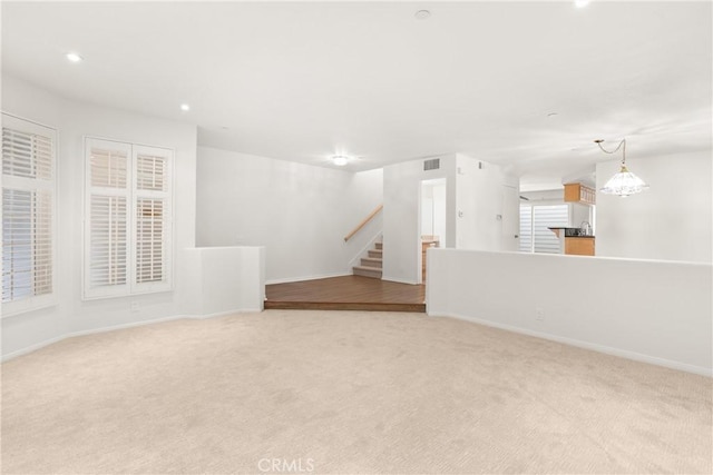 unfurnished living room featuring recessed lighting, baseboards, light carpet, and stairway