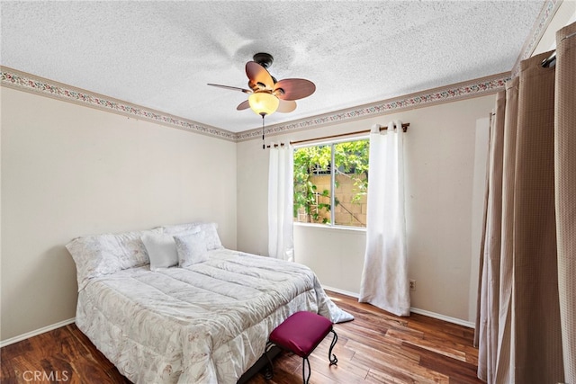 bedroom featuring baseboards, a textured ceiling, and wood finished floors