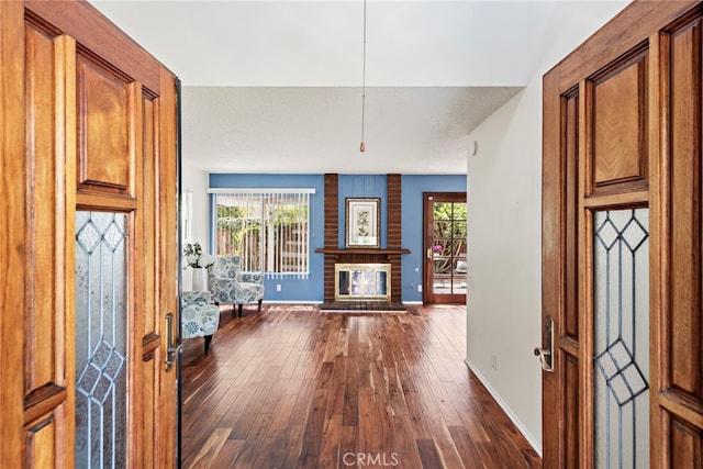 entrance foyer featuring baseboards, a fireplace, and dark wood finished floors